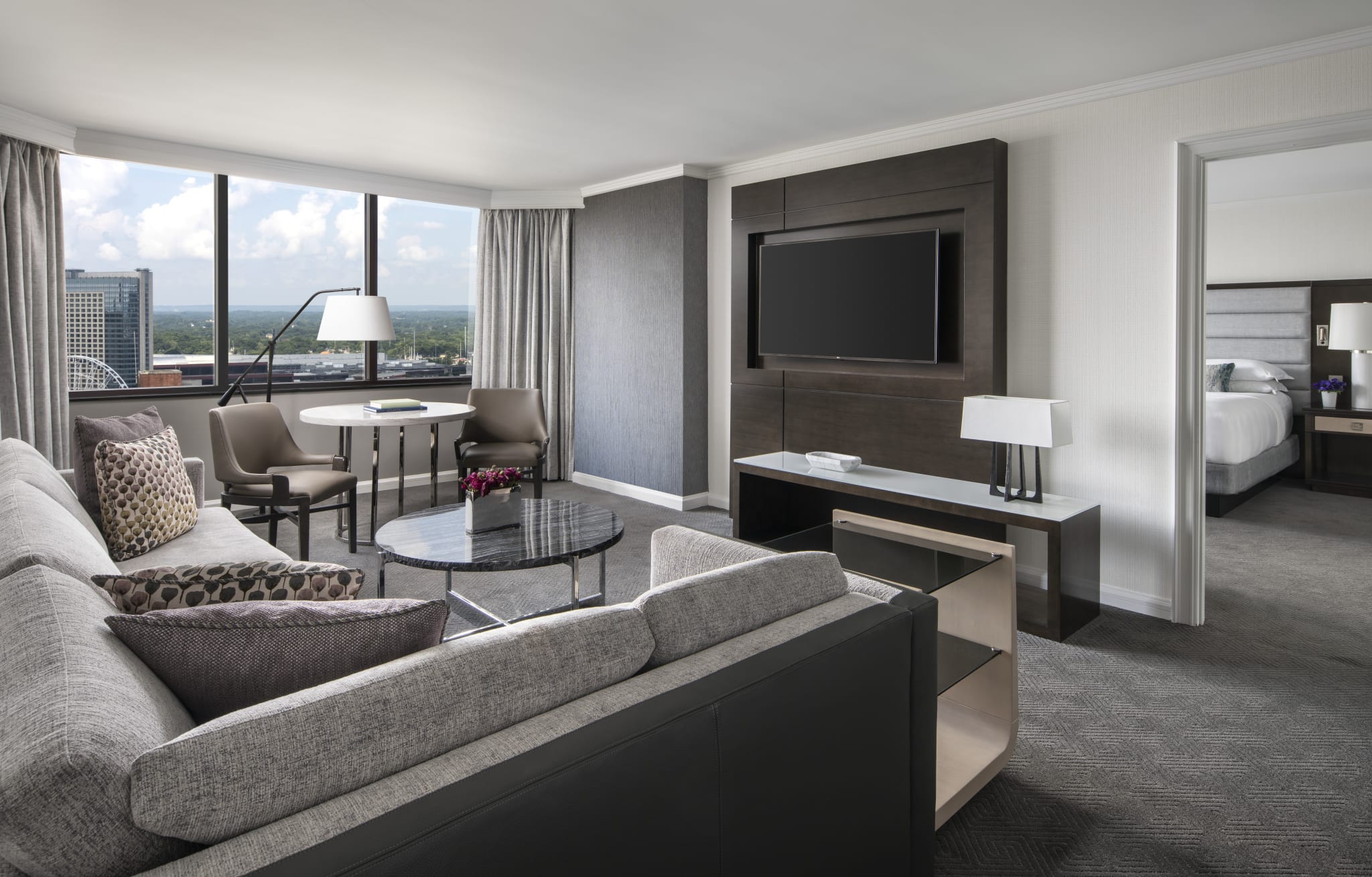 Modern hotel suite with floor-to-ceiling windows, sleek furniture, and city views in Atlanta, Georgia.