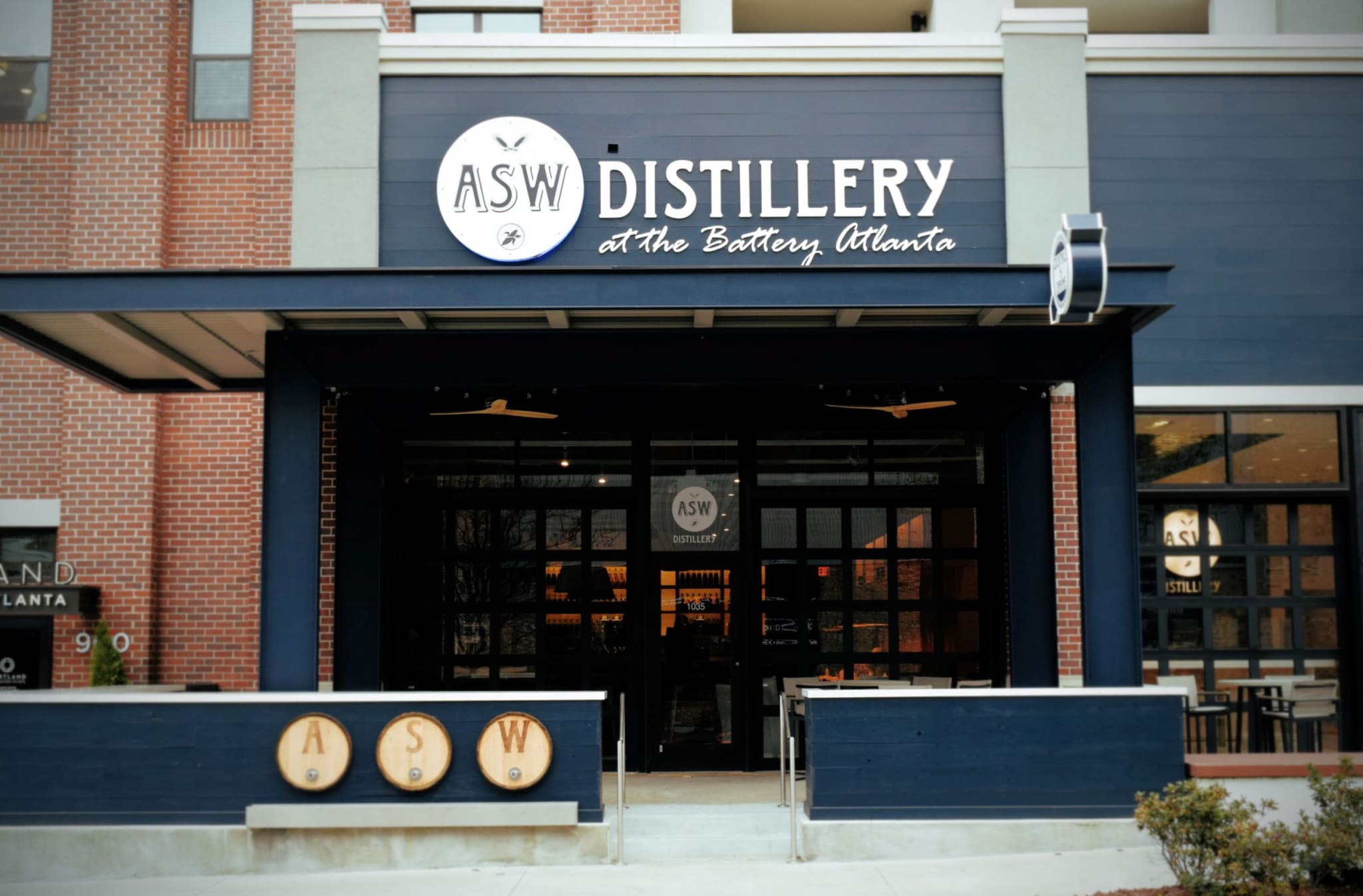 A modern building with a dark blue awning and a sign for ASW Distillery at the Battery Atlanta in Atlanta, Georgia.