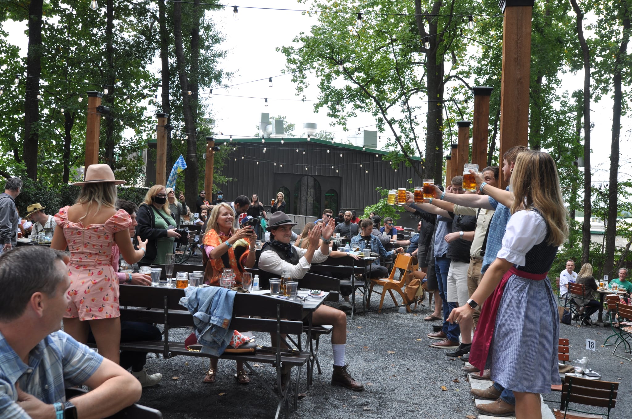 Outdoor beer garden with people in traditional attire raising steins in a toast in Atlanta, Georgia.
