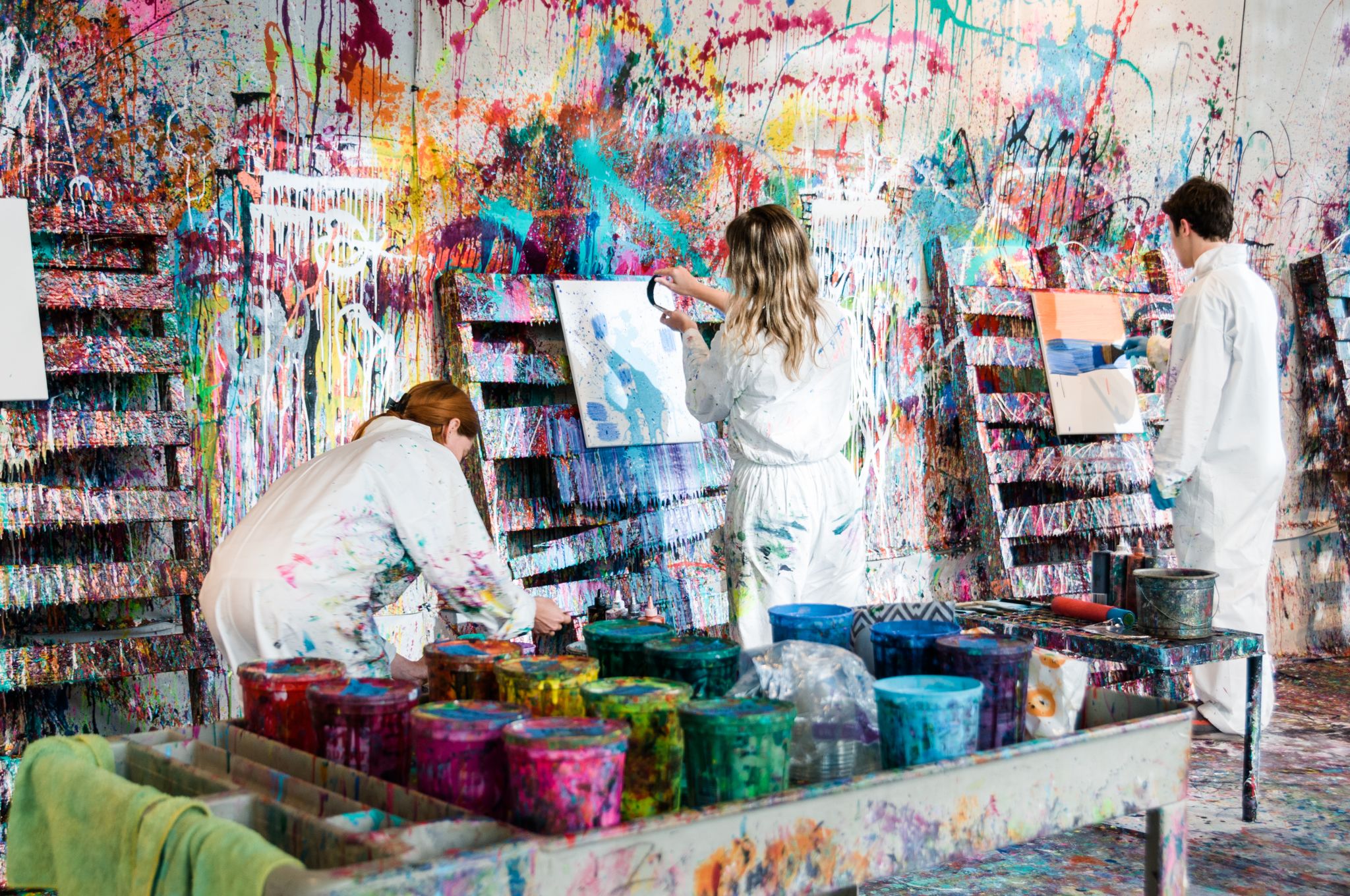 Guía para el mejor verano en Atlanta 5 Three artists in white coveralls paint a vibrant, colorful mural on a wall in Atlanta, Georgia.