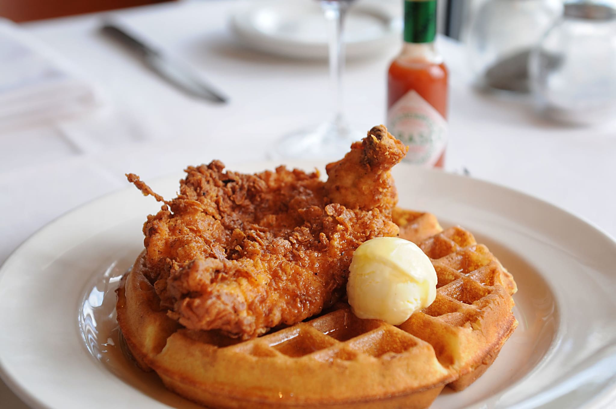 Crispy fried chicken atop a golden waffle with a pat of butter and syrup in Atlanta, Georgia.