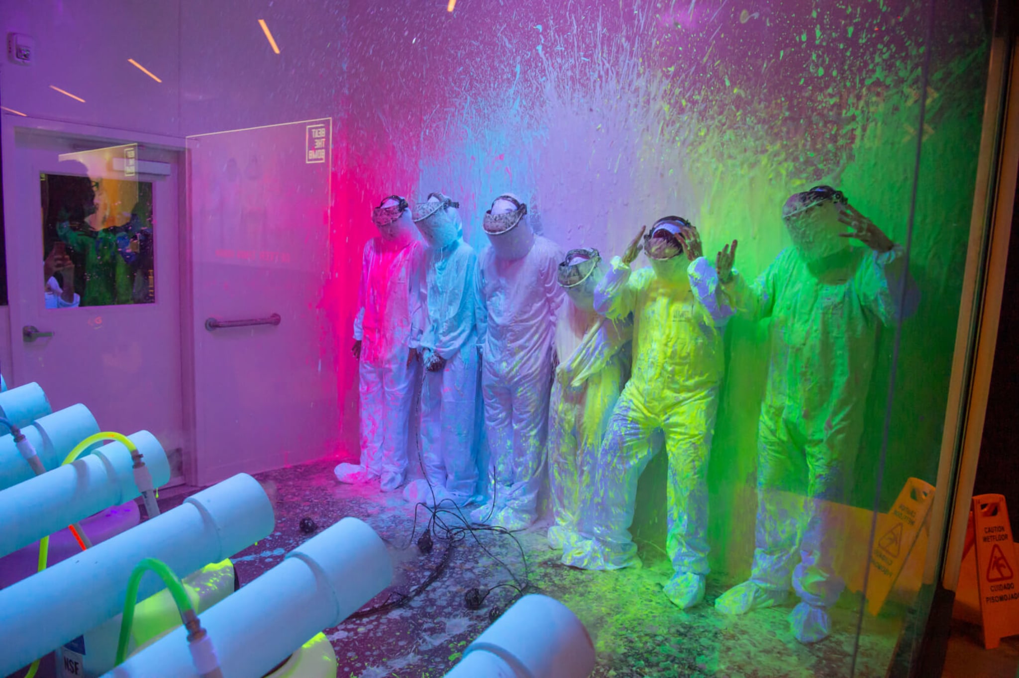 People in hazmat suits stand in a colorful paint-splattered room in Atlanta, Georgia.