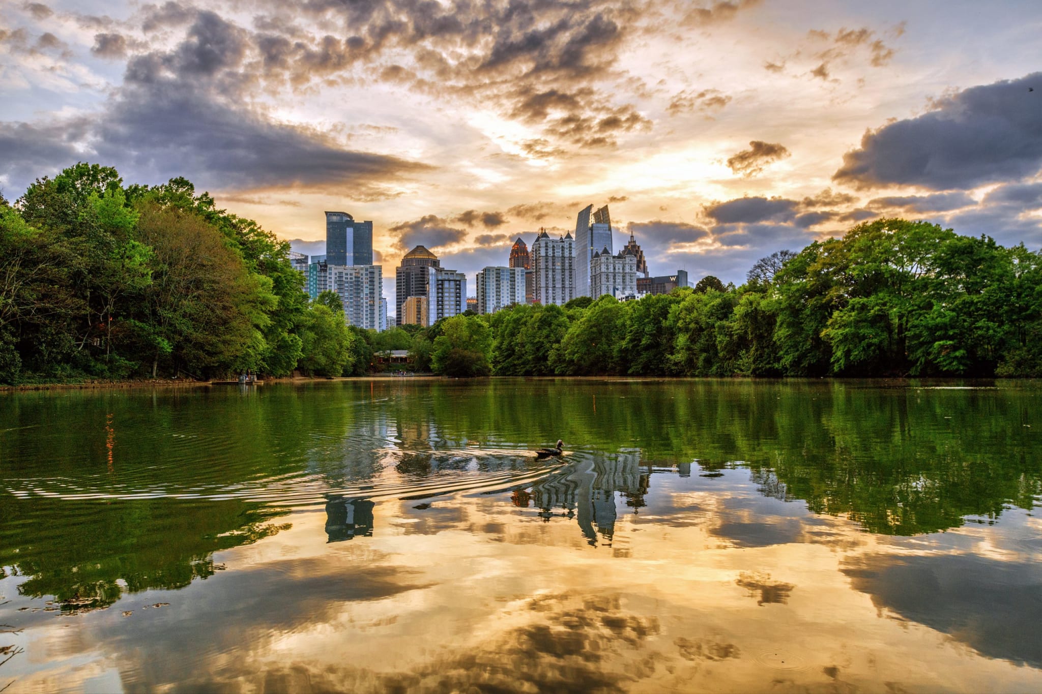 A serene lake reflects a vibrant sunset and a distant city skyline in Atlanta, Georgia.