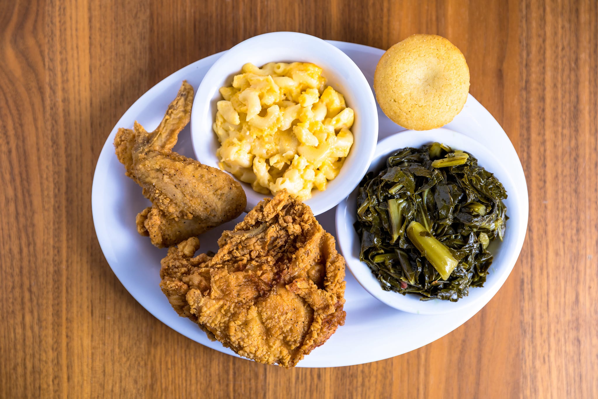 25 Iconic Atlanta Dishes 8 A plate of Southern comfort food featuring fried chicken, macaroni and cheese, collard greens, and a cornbread muffin in Atlanta, Georgia.