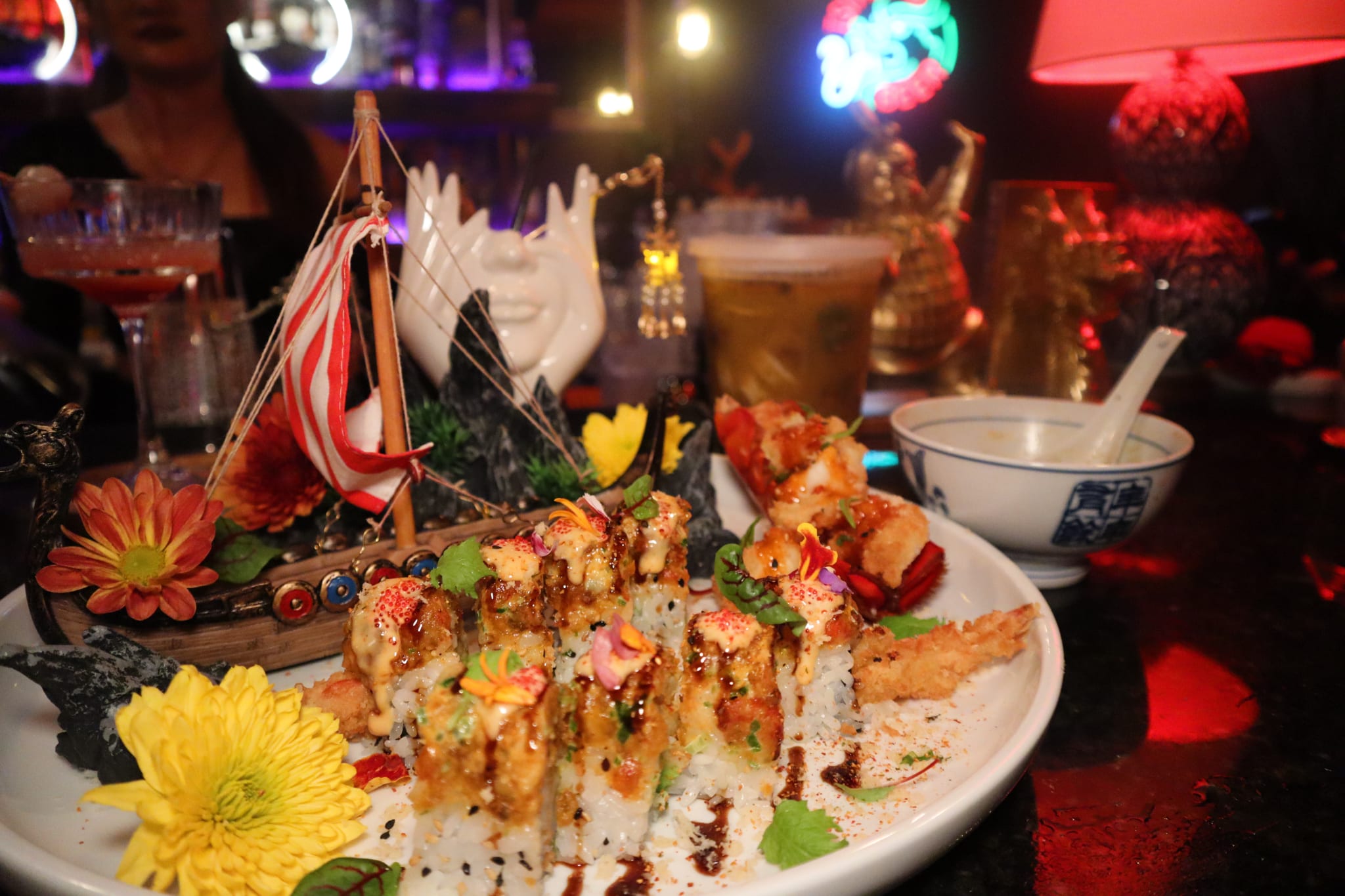 A beautifully presented sushi dish with a miniature Viking ship and colorful flowers in Atlanta, Georgia.