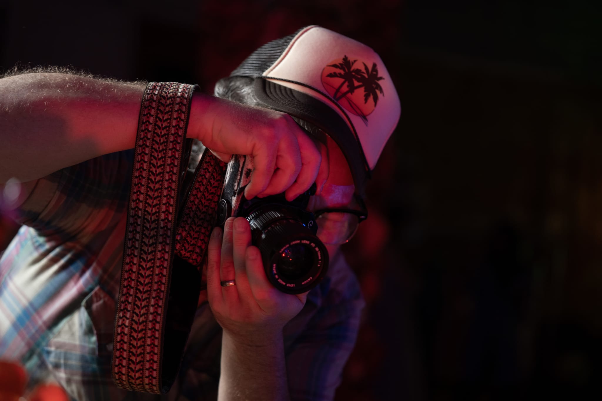 A man wearing a baseball cap with palm trees takes a photo with a camera in Atlanta, Georgia.