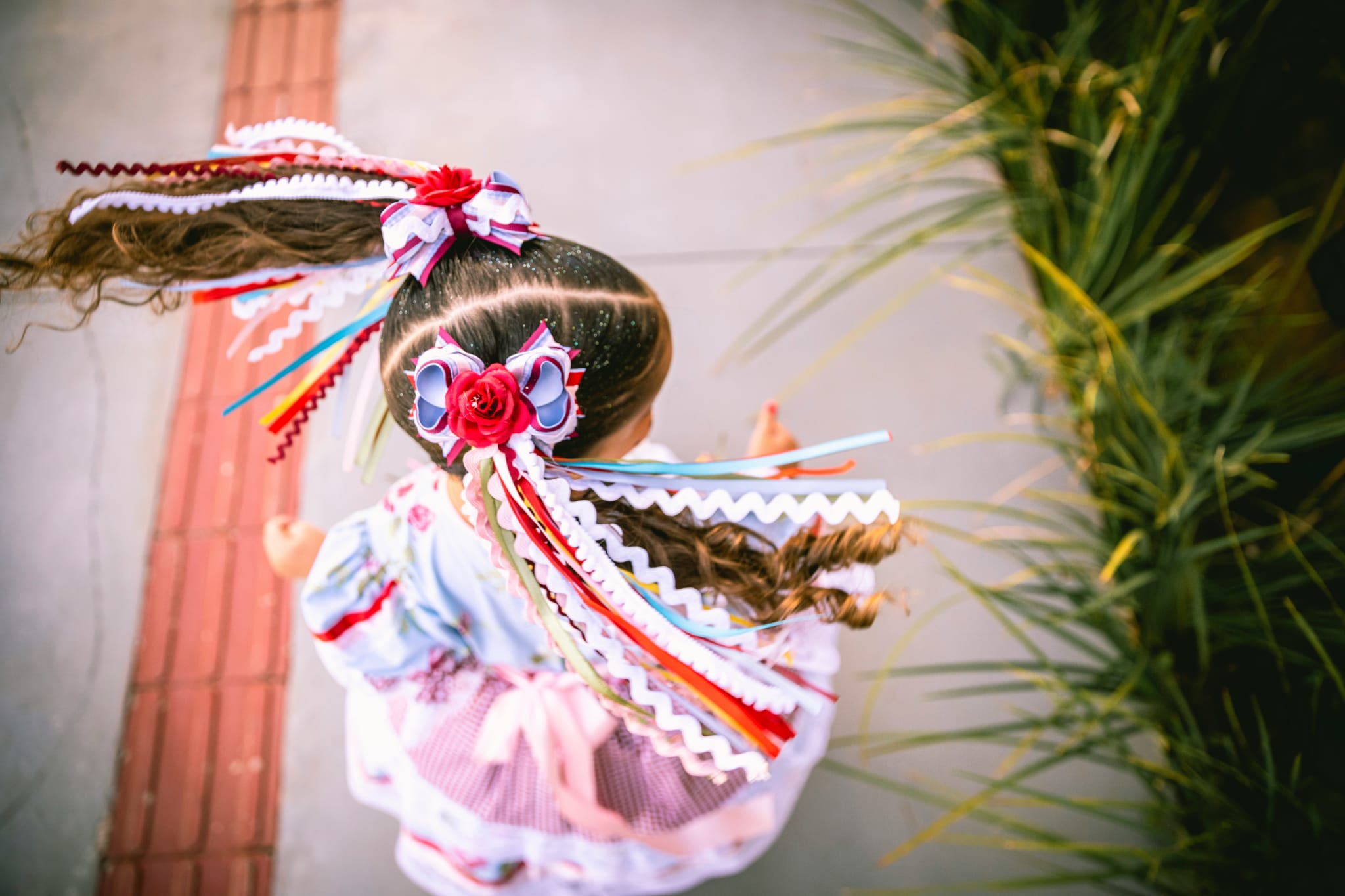 12 Kid-Friendly Things to do during Hispanic Heritage Month in Atlanta 3 A young girl with colorful, curly hair adorned with ribbons and bows walks on a brick path in Atlanta, Georgia.