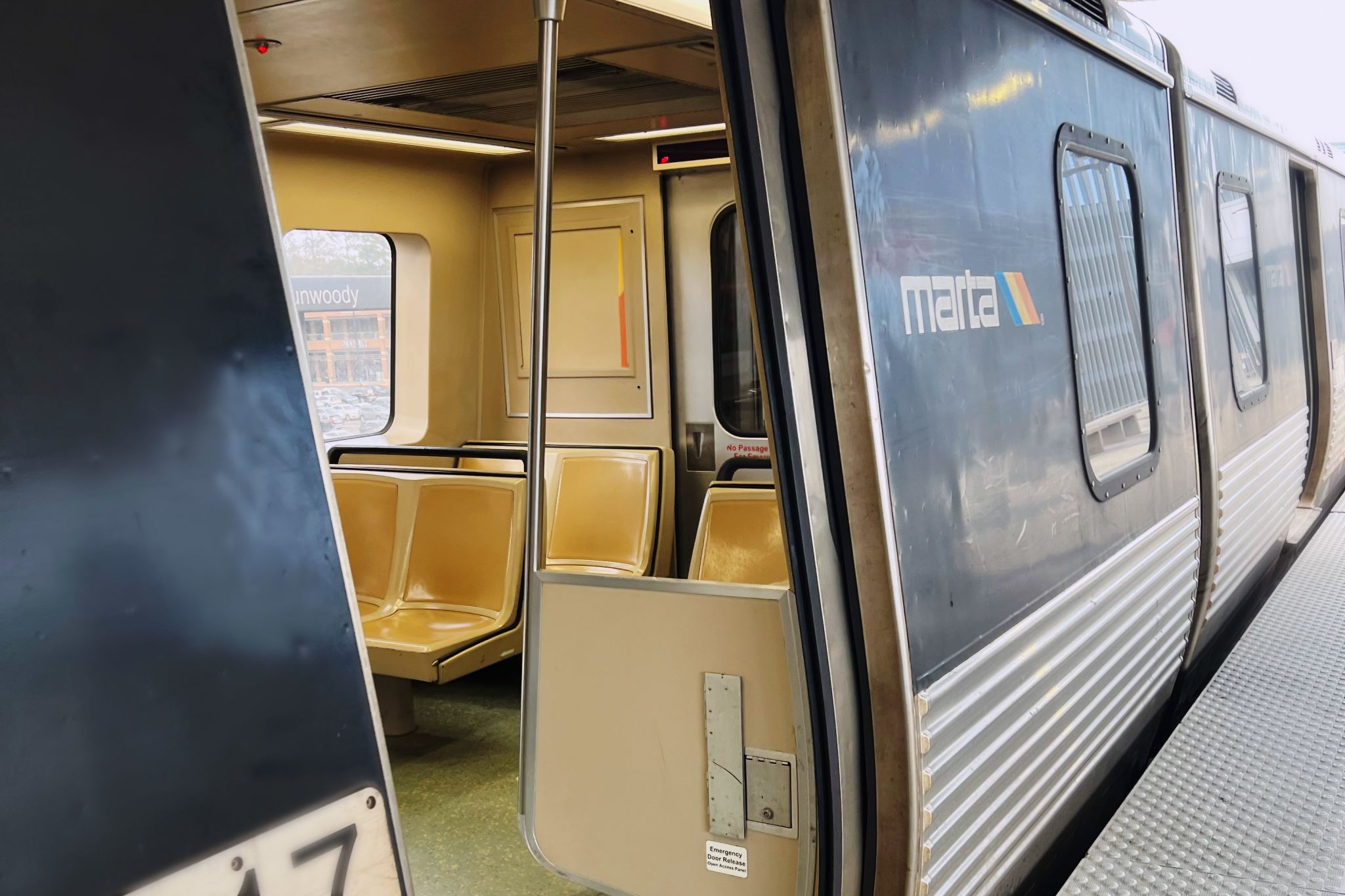 A MARTA train car with open doors, beige seats, and a window view of a station platform in Atlanta, Georgia.