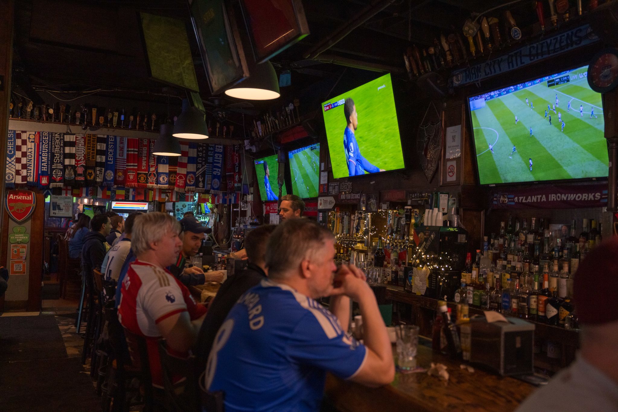 Sports bar patrons watch multiple soccer matches on TVs, surrounded by flags and memorabilia in Atlanta, Georgia.
