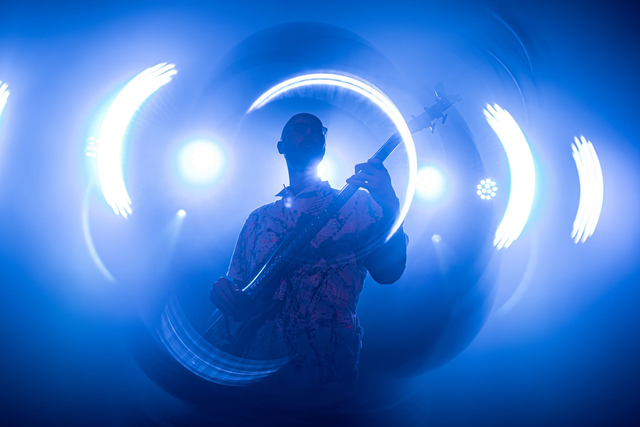 A musician is passionately playing an electric guitar on stage, illuminated by dramatic blue and white light effects that create a mesmerizing, almost ethereal atmosphere in Atlanta, Georgia.
