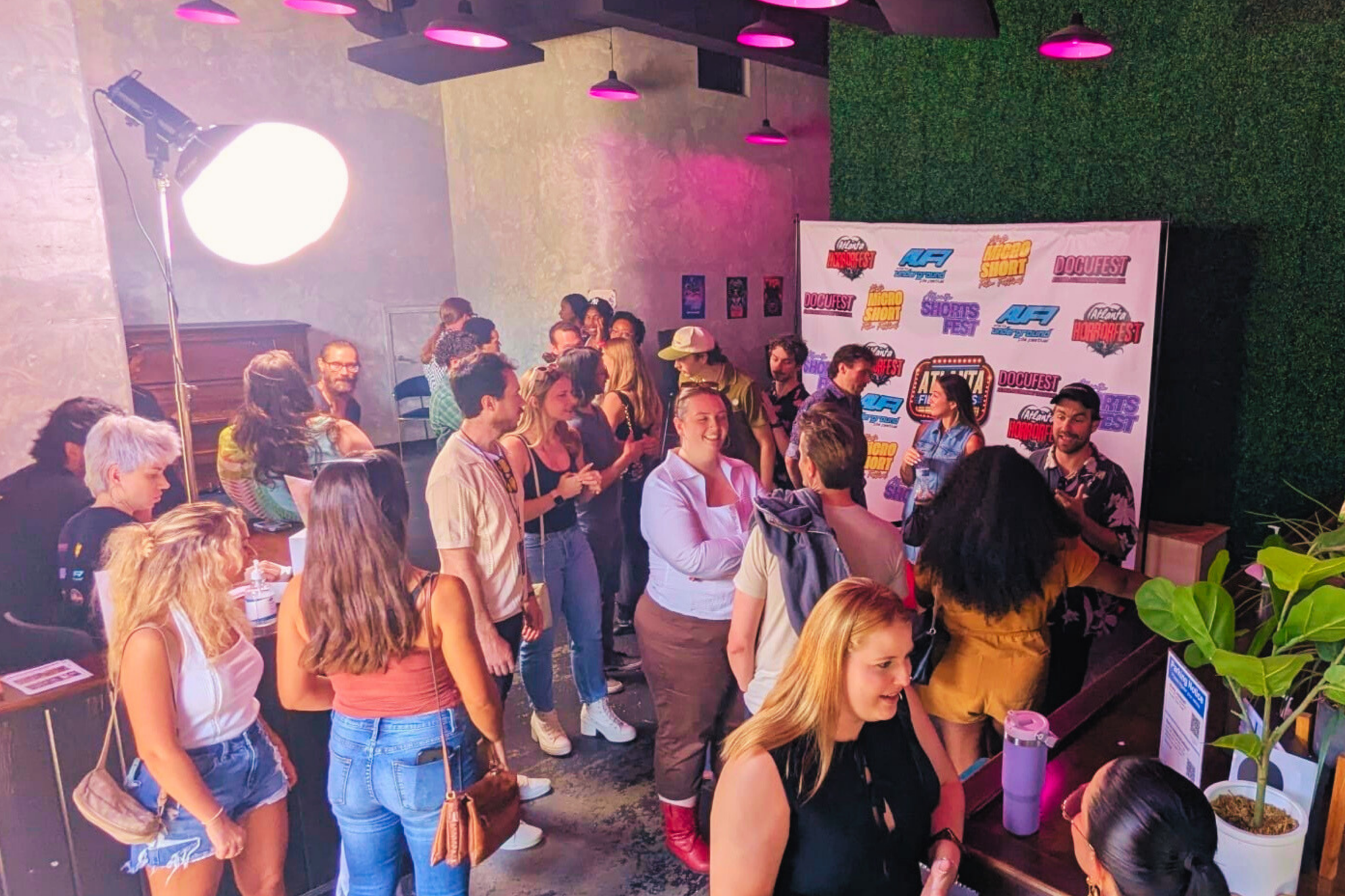 A lively indoor gathering with a diverse crowd of people socializing, surrounded by vibrant decorations and illuminated by colorful lights in Atlanta, Georgia.