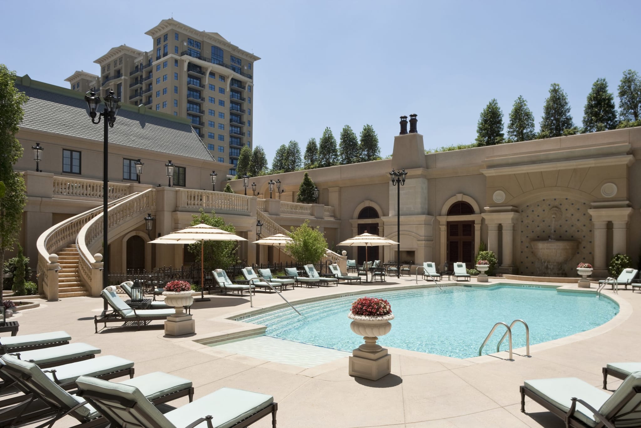 Luxurious outdoor pool area with lounge chairs, umbrellas, and a grand staircase in Atlanta, Georgia.