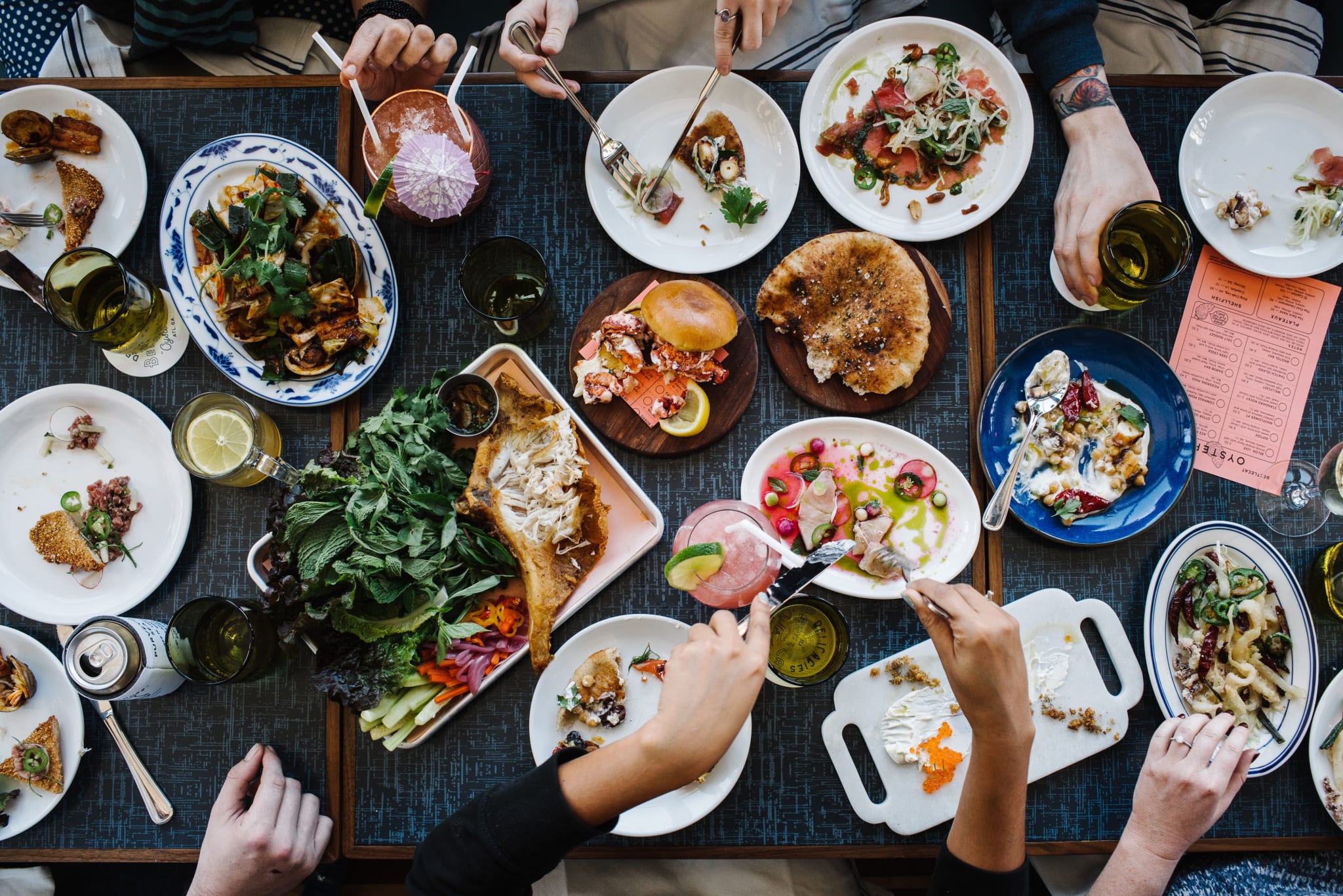 A group of people enjoys a diverse spread of colorful dishes and drinks at a communal meal in Atlanta, Georgia.