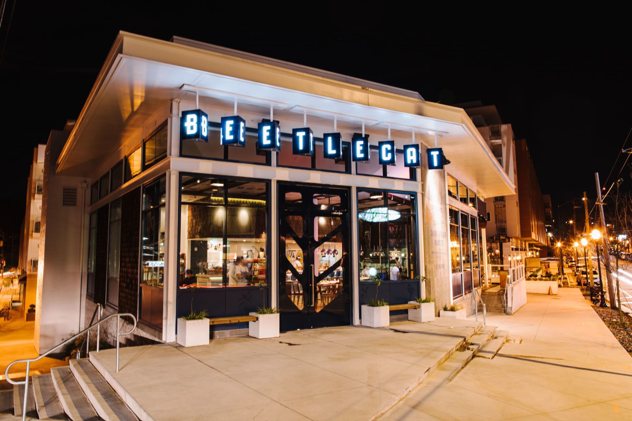 A modern restaurant with a blue neon sign and large windows at night in Atlanta, Georgia.