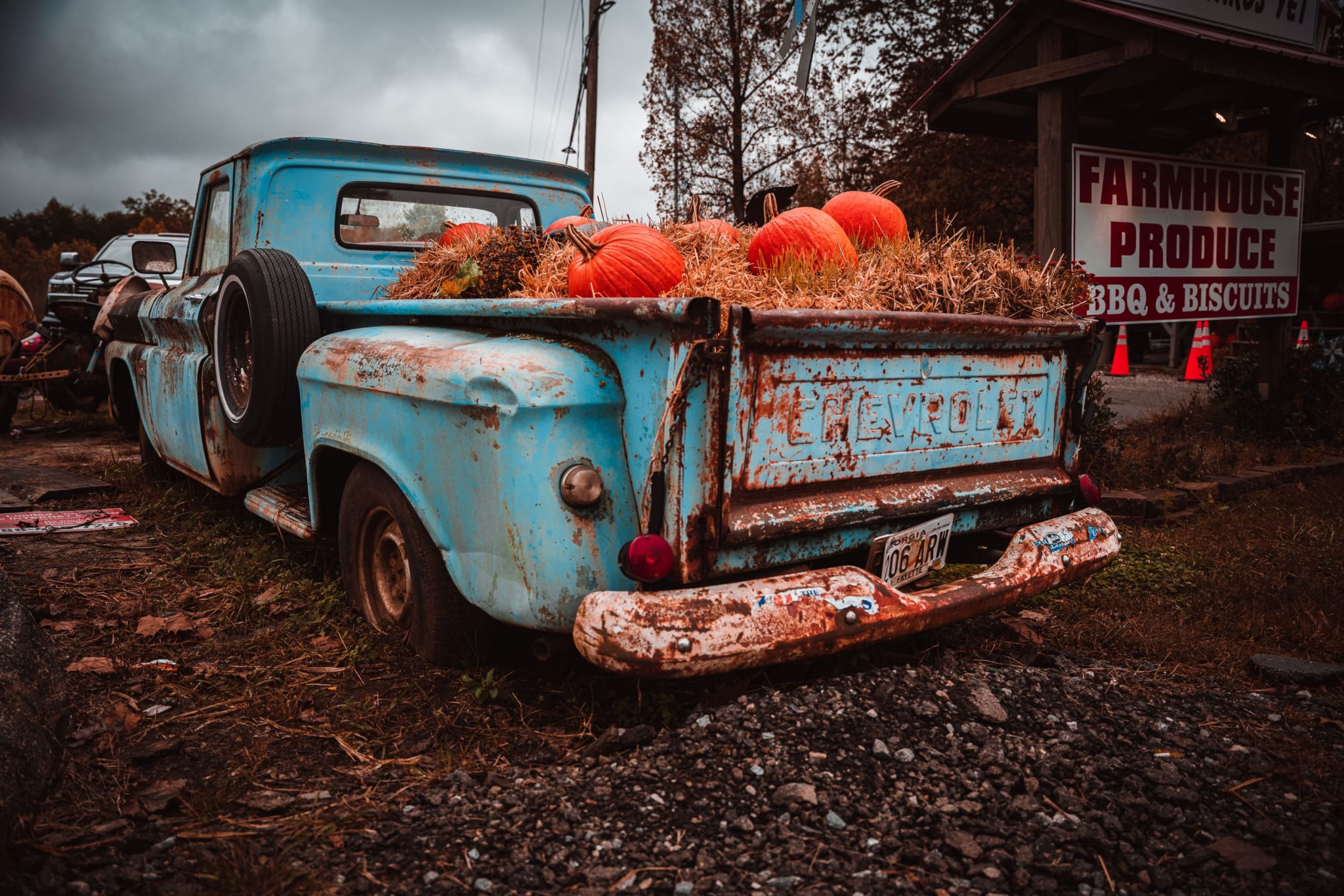 A vintage blue pickup truck filled with pumpkins and hay bales at a farm stand in Atlanta, Georgia.