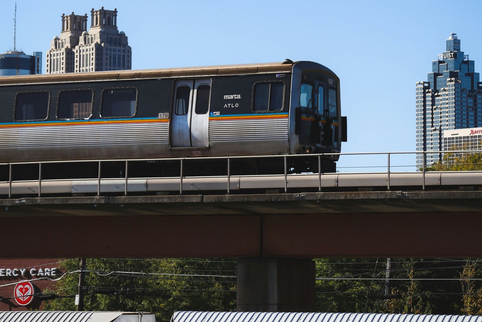 A commuter train travels on an elevated track above a cityscape with skyscrapers in the background in Atlanta, Georgia.