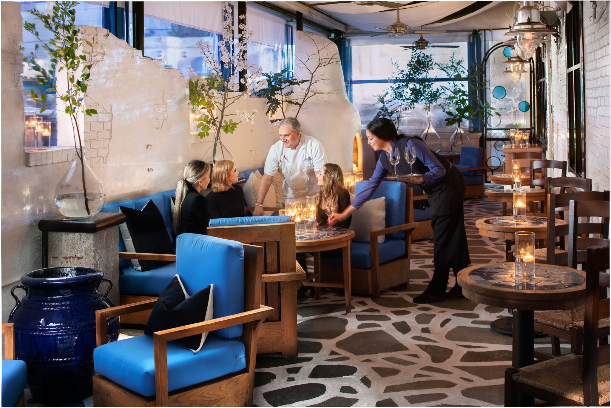 A cozy restaurant interior with blue seating, candlelit tables, and a chef serving guests in Atlanta, Georgia.