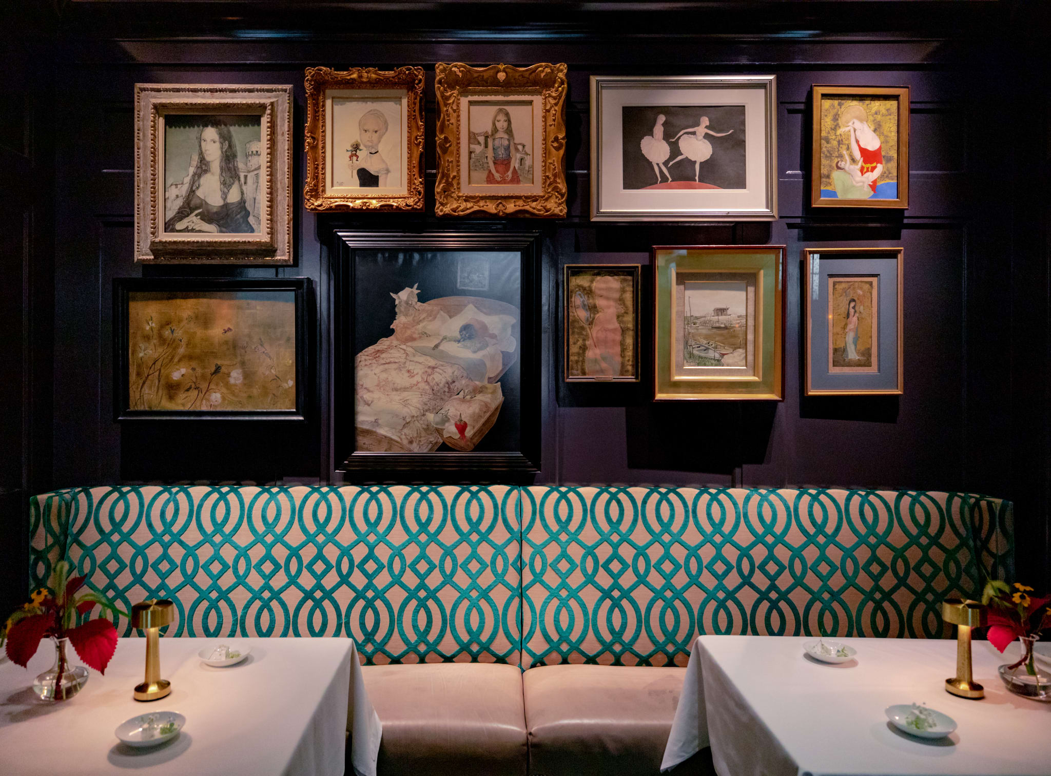 Elegant dining room with ornate gold-framed paintings on dark walls and patterned bench seating in Atlanta, Georgia.