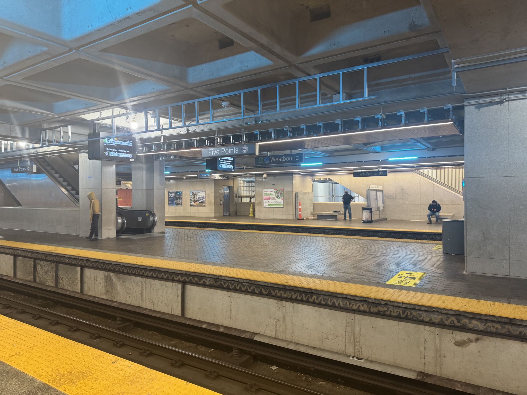 A subway station platform with yellow tactile paving, a train track, and a few passengers waiting in Atlanta, Georgia.
