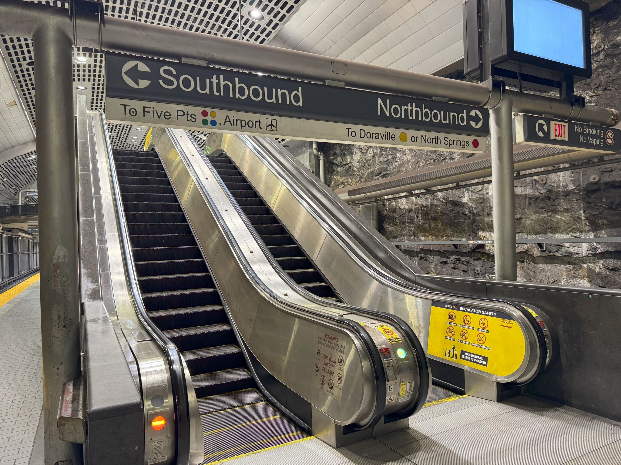 Two escalators in a subway station with signs indicating directions to various platforms and exits in Atlanta, Georgia.