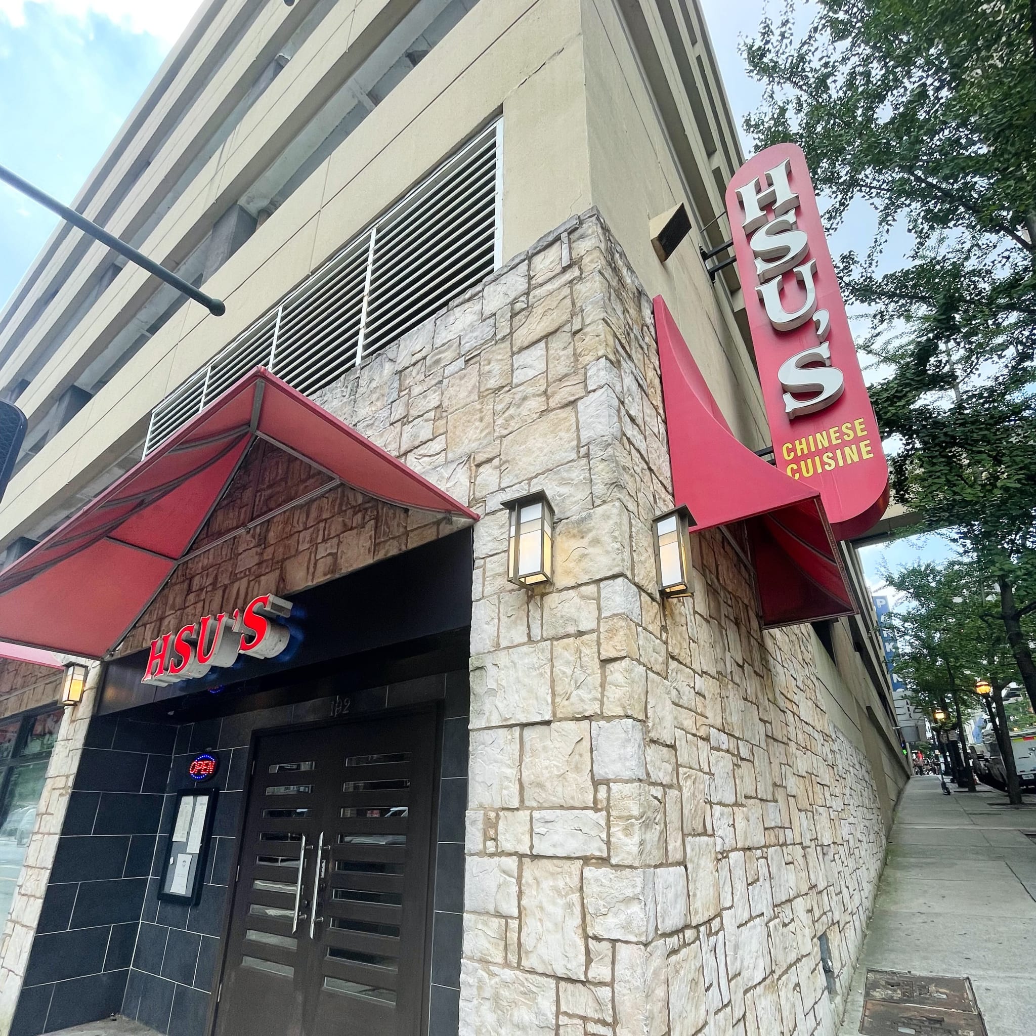 A modern Chinese restaurant with a red awning and stone facade on a city street in Atlanta, Georgia.