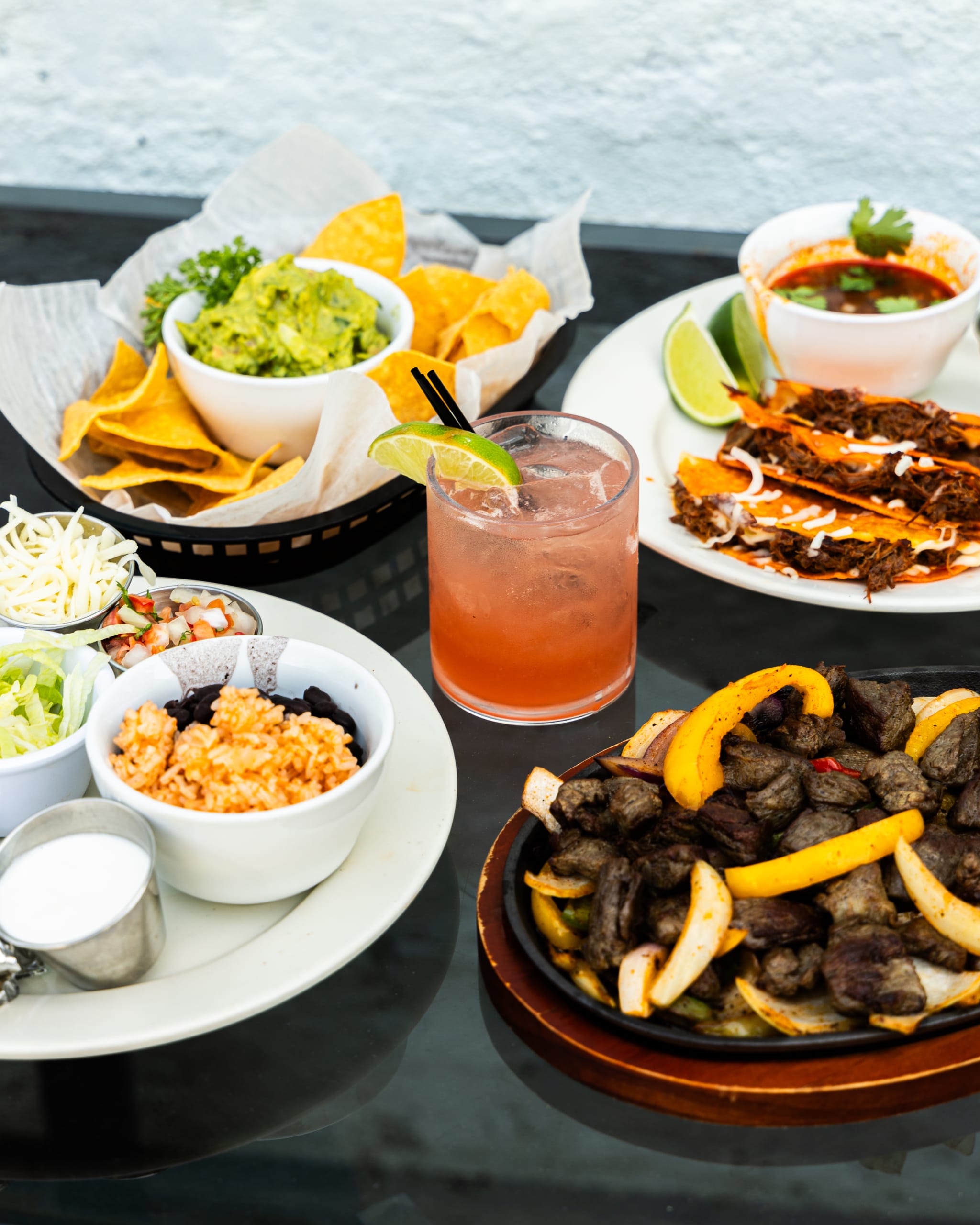 Summerhill 3 A table set with a variety of Mexican dishes including tacos, guacamole, chips, and a colorful cocktail in Atlanta, Georgia.