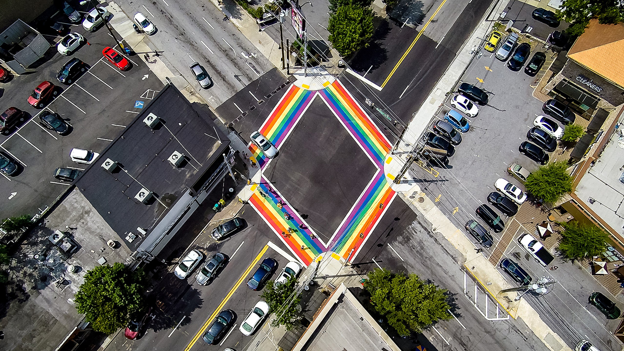 Aerial view of a city intersection with a vibrant rainbow crosswalk and surrounding parking lots in Atlanta, Georgia.