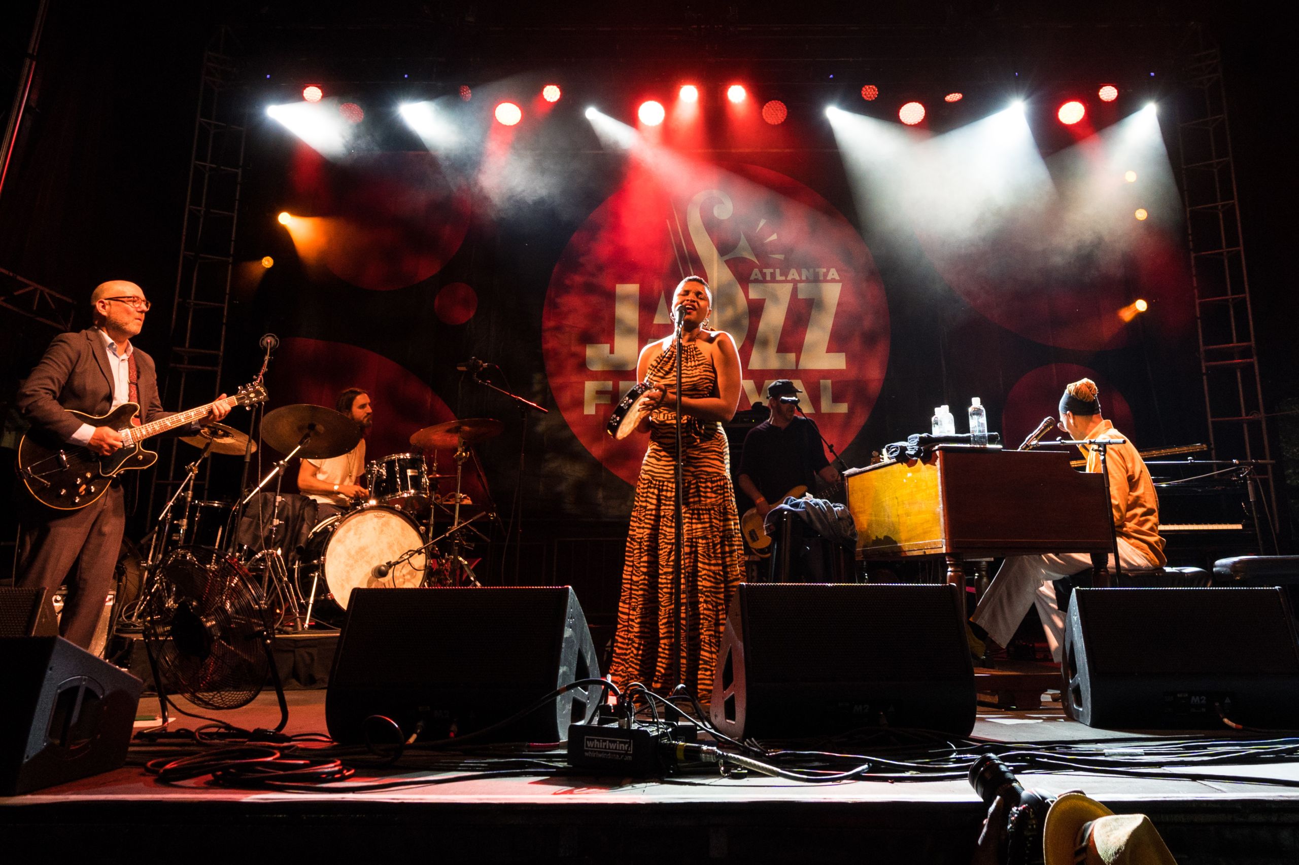 Band on stage with woman in middle as lead singer. 