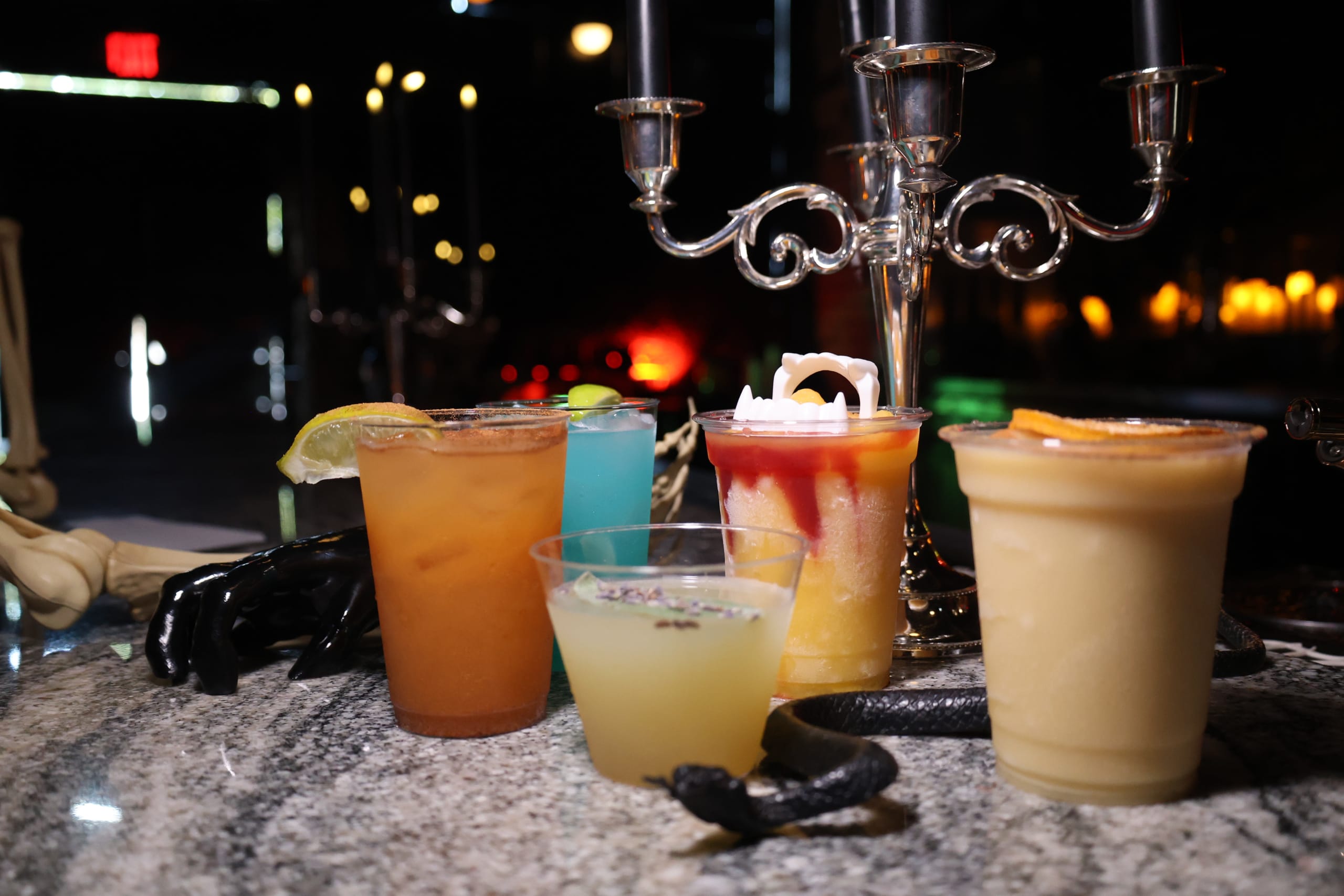 Five colorful Halloween-themed cocktails with spooky decorations on a dark countertop in Atlanta, Georgia.