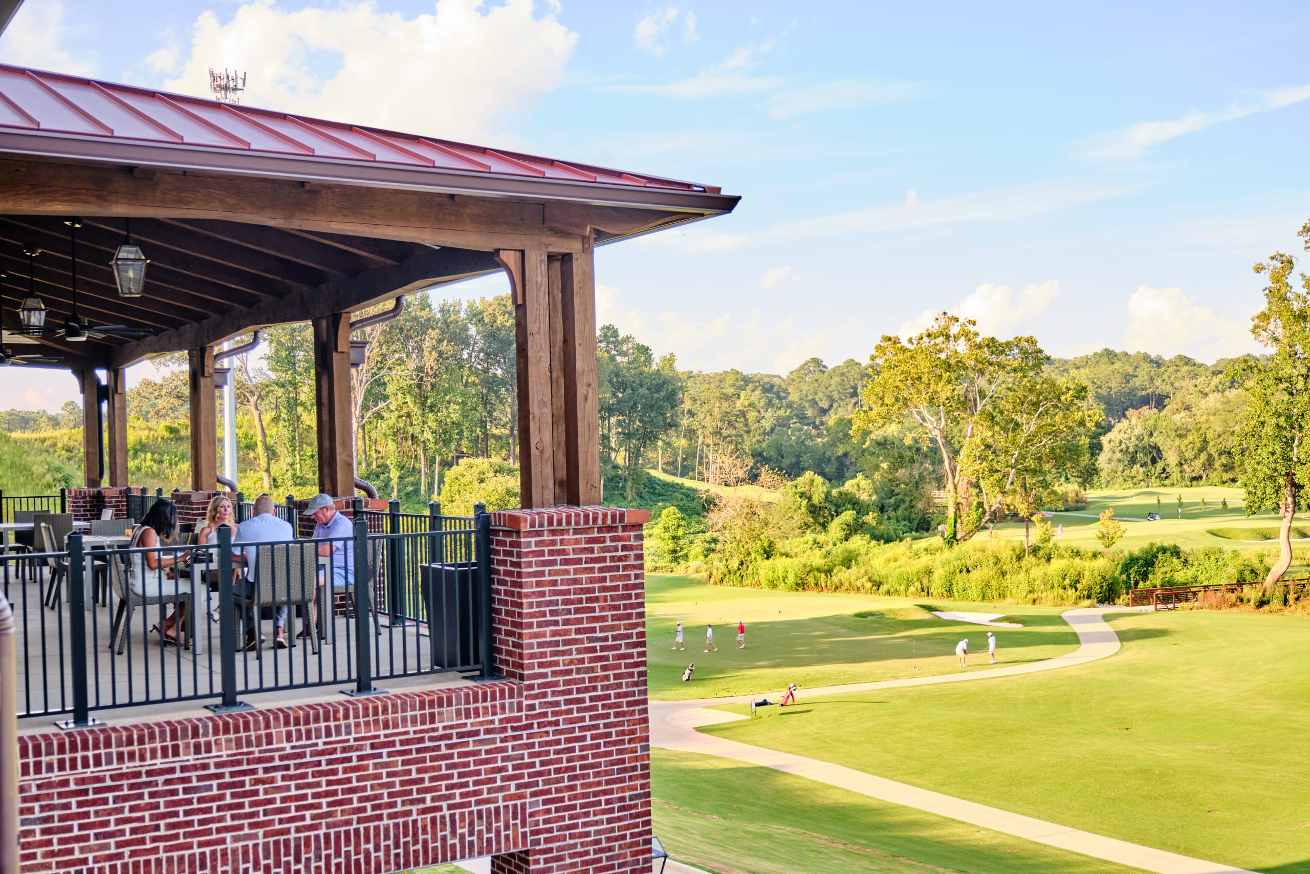 Easter: Things to Do in Atlanta 2 A brick building with a red roof overlooks a golf course where people are playing and walking in Atlanta, Georgia.