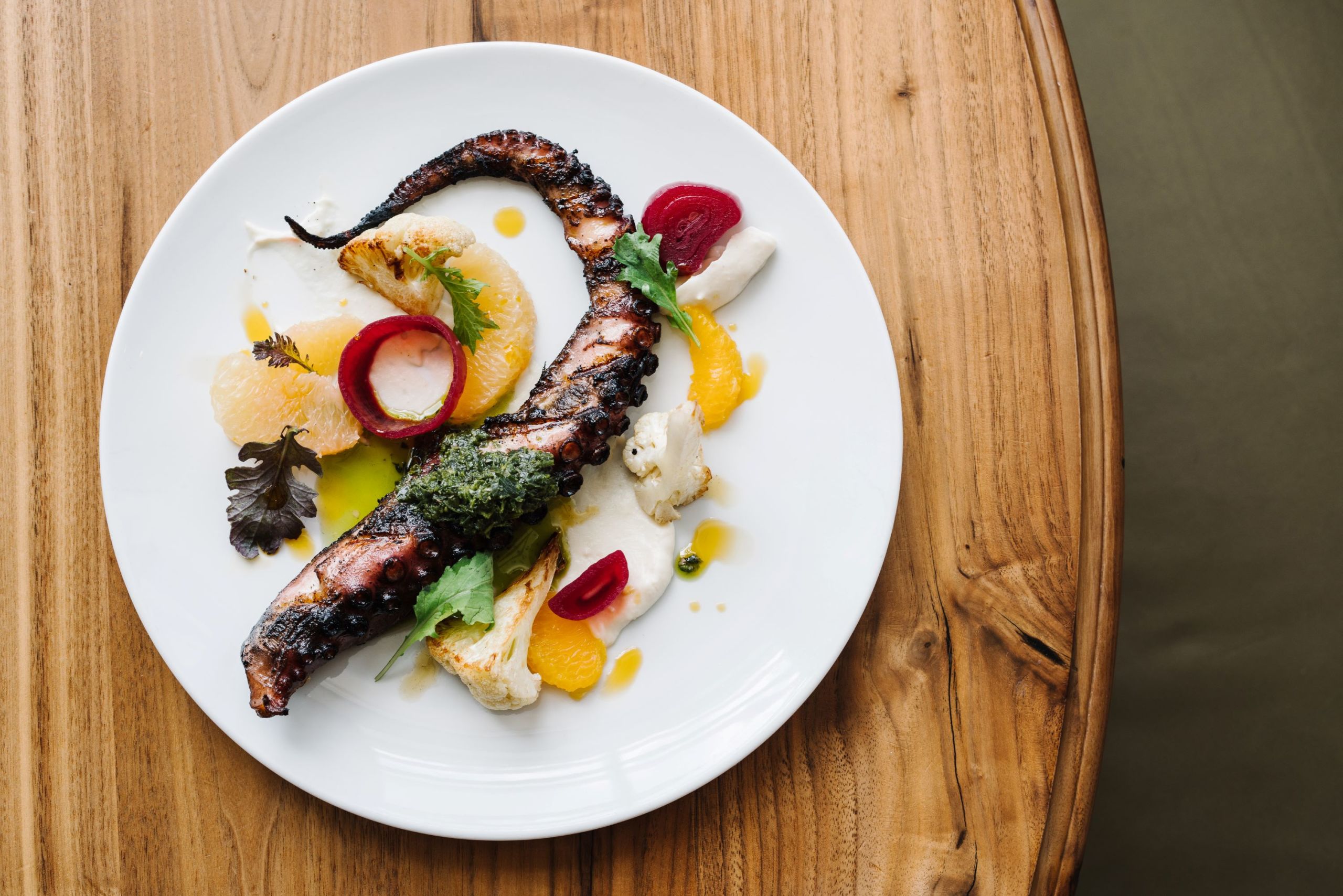 White plate over wood table. Octopus in the dish. 