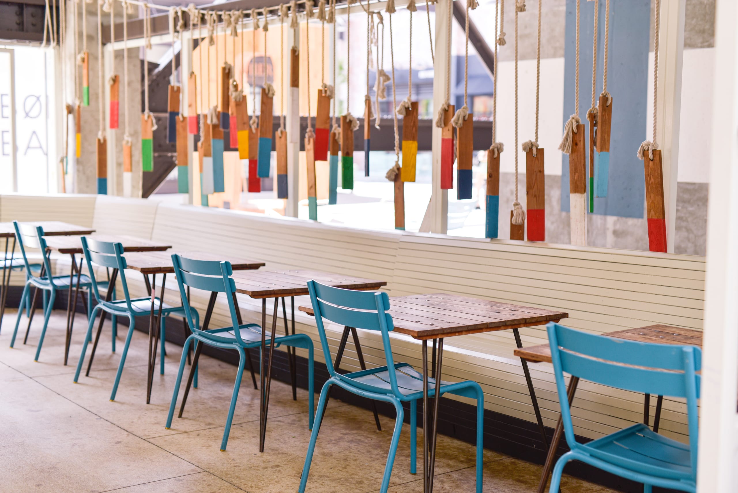 A modern cafe interior with colorful wooden decorations and blue metal chairs in Atlanta, Georgia.