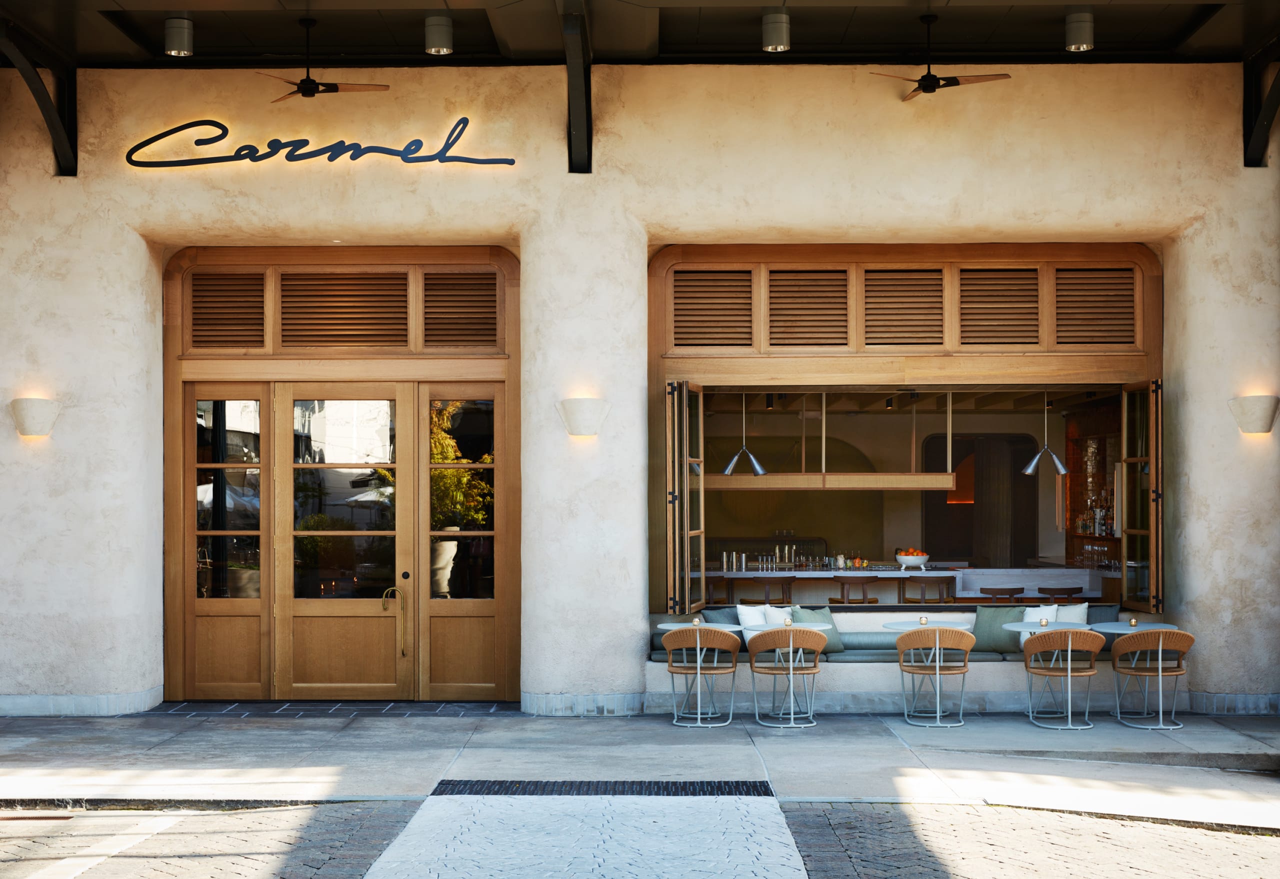 A stylish restaurant entrance with wooden doors, outdoor seating, and a modern interior in Atlanta, Georgia.