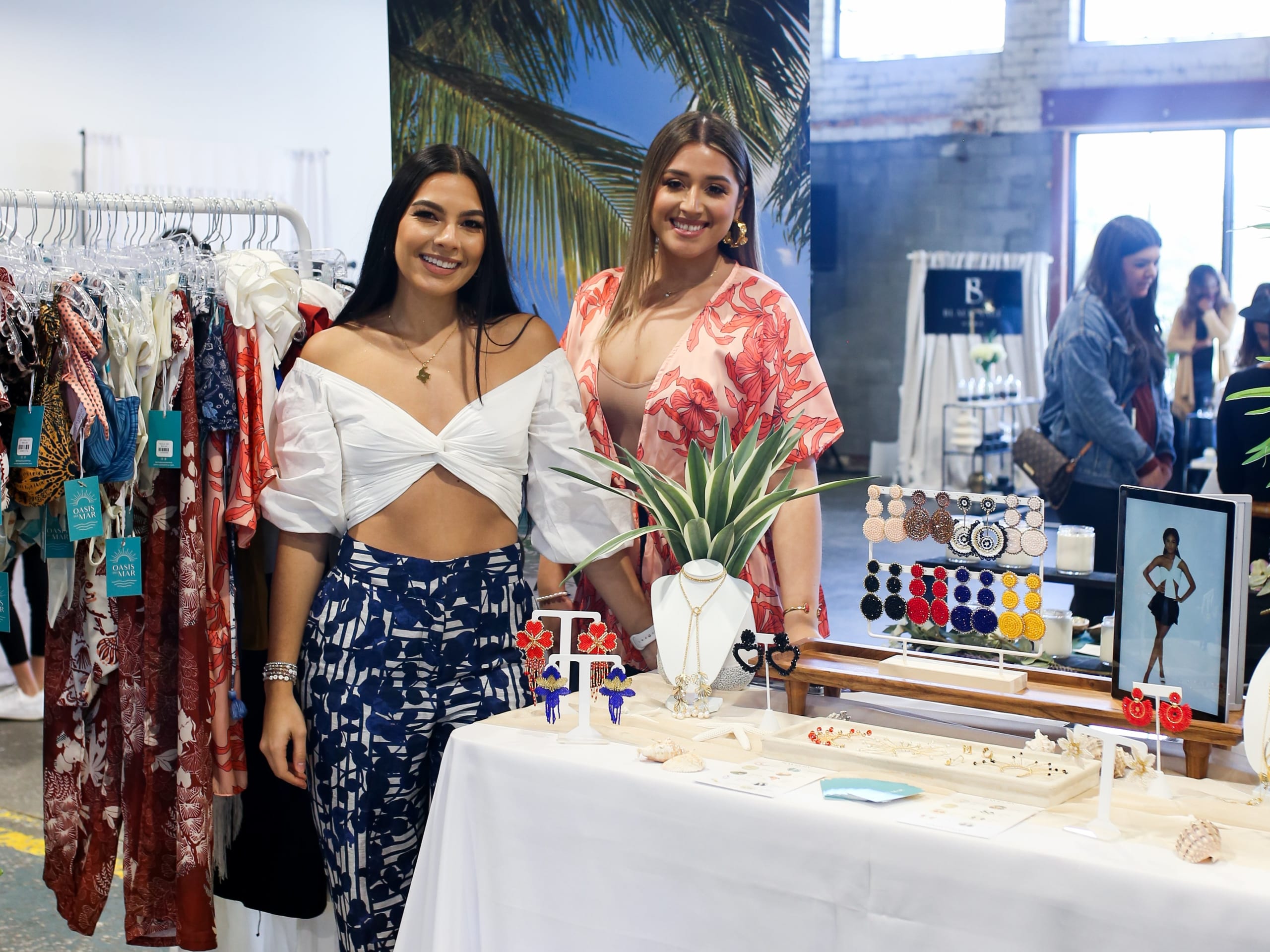 Two women stand behind a table filled with colorful jewelry and accessories at a market in Atlanta, Georgia.