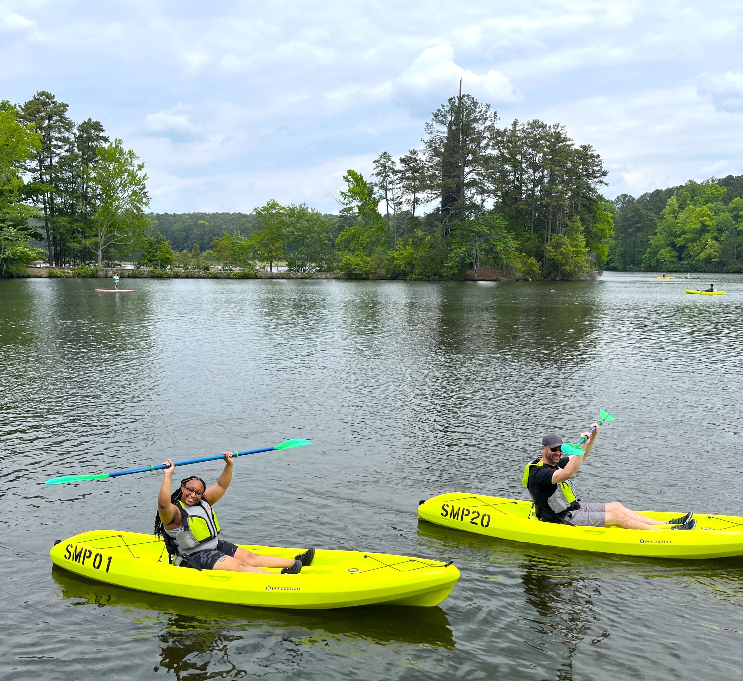 Two people in yellow kayaks paddle on a calm lake surrounded by trees in Atlanta, Georgia.