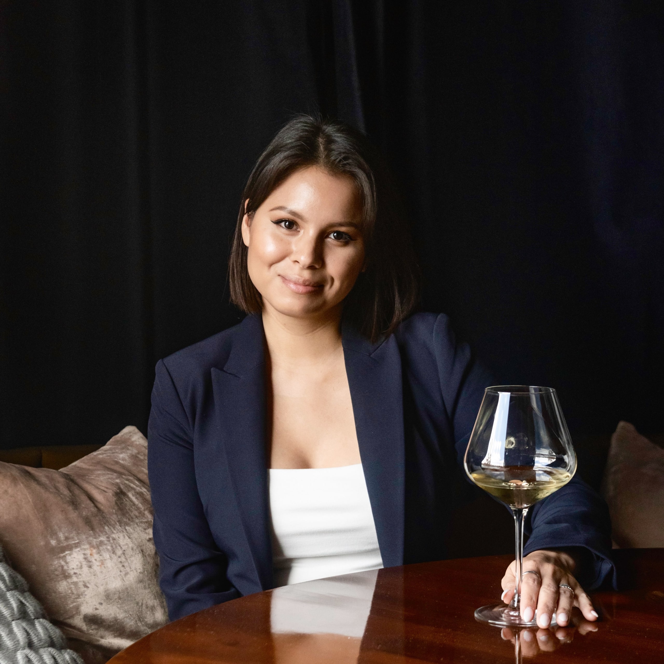 From Cocktails to Cuisine: Exploring Signia by Hilton Atlanta’s Food Scene 3 A woman in a navy blazer and white top holds a glass of white wine at a table in Atlanta, Georgia.