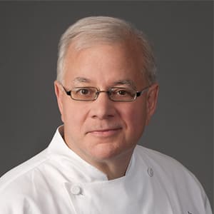 A professional portrait of a white-haired man wearing glasses and a chef's coat in Atlanta, Georgia.