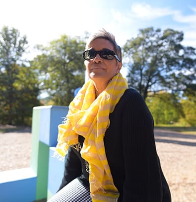 Camille Love 1 A woman with short hair and sunglasses sits outdoors, wearing a yellow scarf in Atlanta, Georgia.