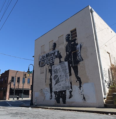 Camille Love 2 A mural on a building depicts two figures holding signs with social messages in Atlanta, Georgia.