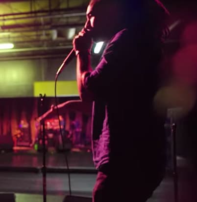 HeaveN Beatbox 1 A musician with dreadlocks performs on stage, holding a microphone and playing a guitar in Atlanta, Georgia.