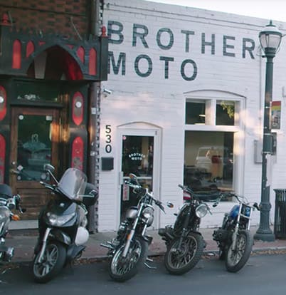 CLAVVS 1 Several motorcycles parked outside a white building with 'Brother Moto' signage in Atlanta, Georgia.