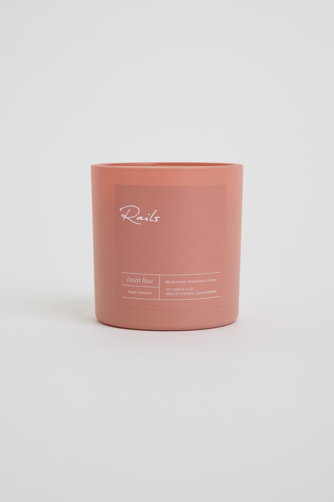A cylindrical candle in a soft pinkish-orange hue with a minimalist label featuring cursive text in Atlanta, Georgia.