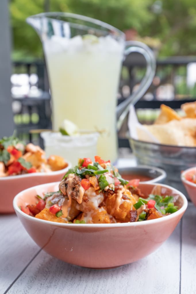 A table set with colorful Mexican-inspired dishes, including tater tots, salsa, and margaritas in Atlanta, Georgia.