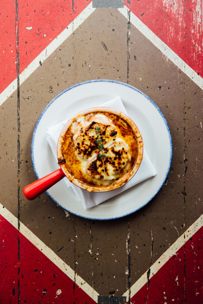 A bowl of French onion soup with a golden-brown crust and a sprig of thyme on top in Atlanta, Georgia.