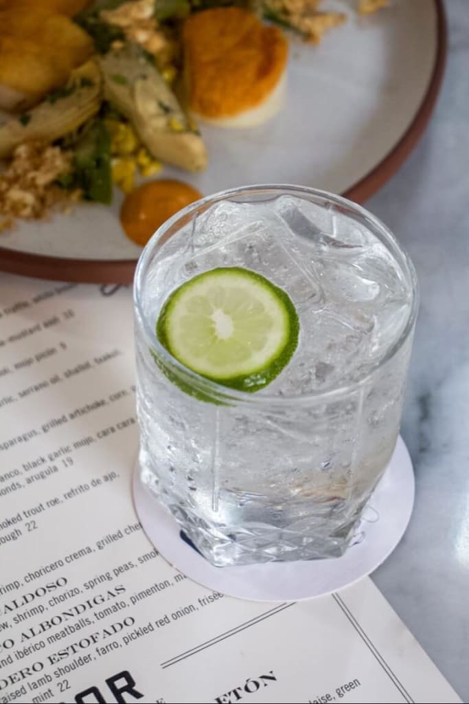 A glass of sparkling water with a lime wedge on a coaster next to a menu in Atlanta, Georgia.