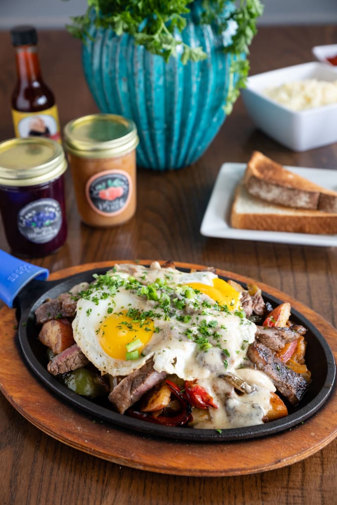 A hearty breakfast skillet with eggs, steak, peppers, and potatoes topped with gravy in Atlanta, Georgia.