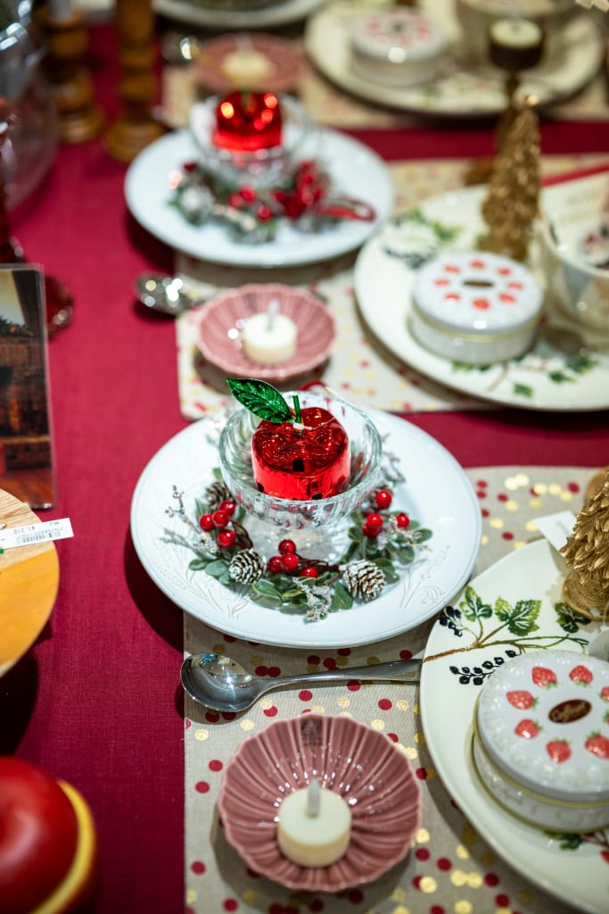 A festive table setting with red and gold Christmas decorations, candles, and fruit in Atlanta, Georgia.