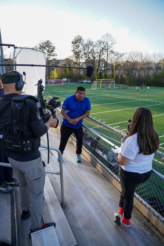 A film crew is setting up to record a soccer game on a sunny day in Atlanta, Georgia.