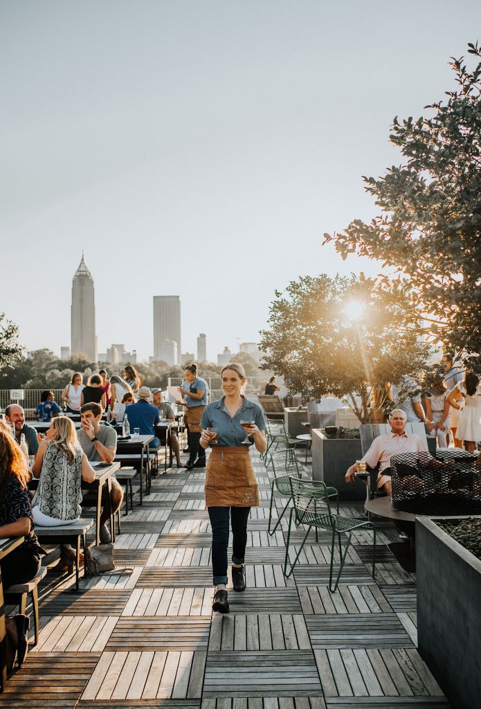 A woman serves drinks on the patio of 9 Mile Station, a rooftop beer garden at Ponce City Market in Atlanta.