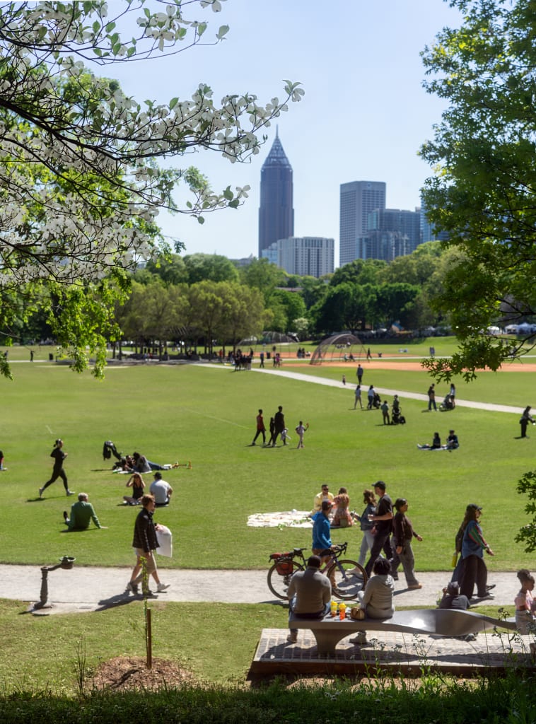 A bustling city park with people enjoying a sunny day, surrounded by trees and skyscrapers in Atlanta, Georgia.